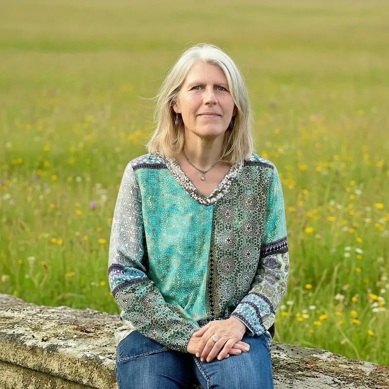 Veronique Jeanne assise dans un champ fleuri.